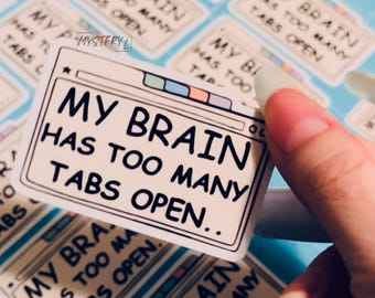 May include: A sticker with the text "MY BRAIN HAS TOO MANY TABS OPEN" in black font. The sticker is rectangular with a white background and a browser window design. Other stickers with the same text are visible in the background.