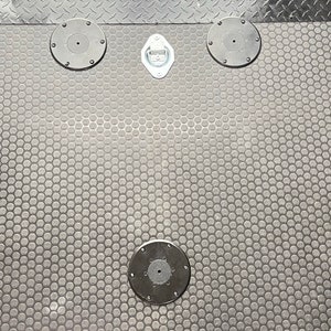 May include: A black rubber floor mat with a hexagonal pattern and four black metal tie-down rings.