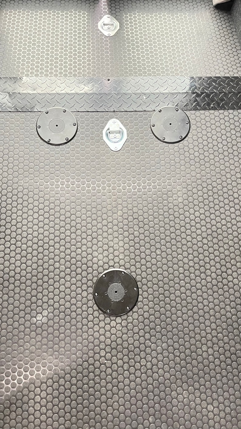 May include: A black rubber floor mat with a hexagonal pattern and four black metal tie-down rings.