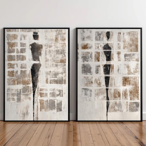 Puede incluir: Dos pinturas abstractas enmarcadas. Cada una presenta una figura de silueta negra sobre un fondo texturizado de cuadrados blancos, marrones y grises. La obra de arte está encerrada en un marco negro, creando una estética moderna.