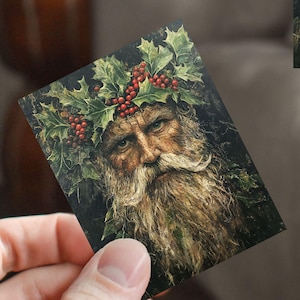 May include: A painting of a man with a long white beard and a crown of holly leaves and red berries. The man's face is weathered and his eyes are closed. The background is a dark green forest.