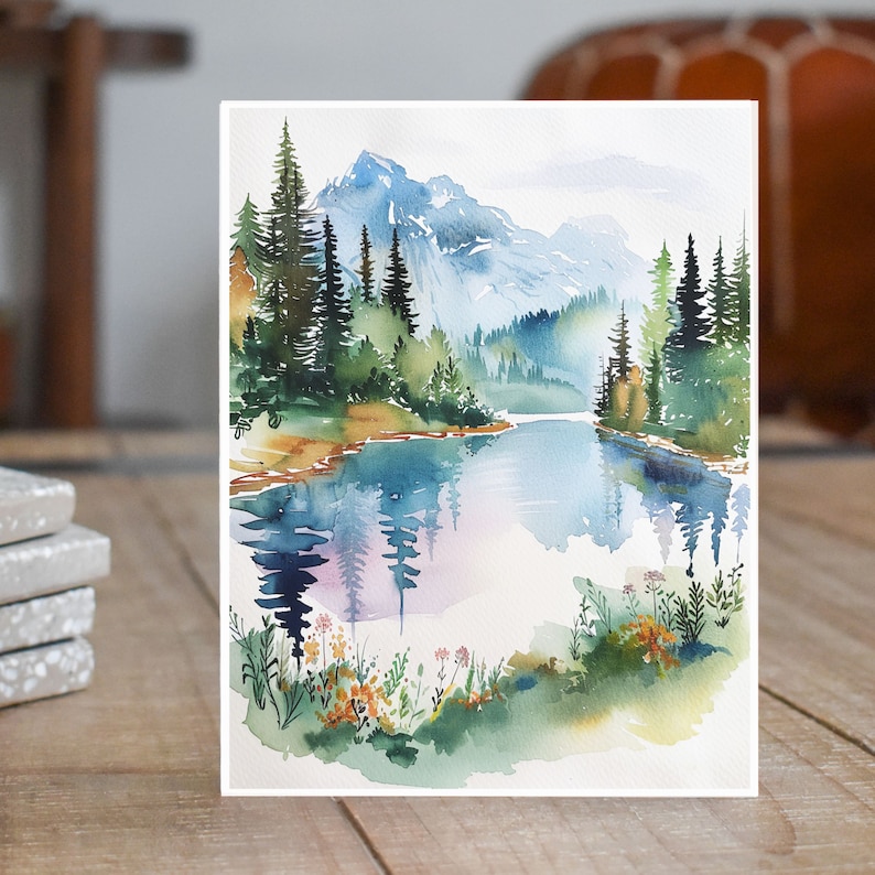 May include: Watercolor painting of a mountain lake scene with a reflection of the trees and mountains in the water. The painting features a blue lake, green trees, and a light blue sky.
