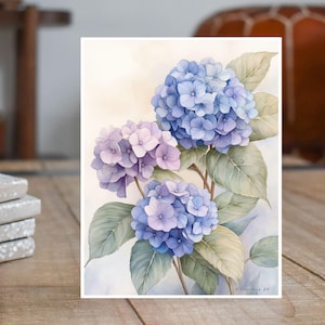 May include: Watercolor painting of three blue and purple hydrangeas with green leaves. The flowers are in bloom and the painting has a soft, romantic feel.