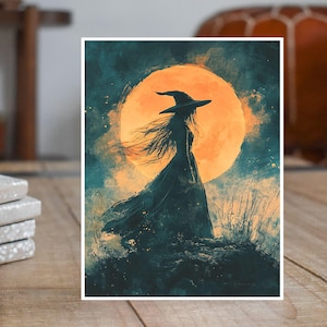 May include: A watercolor print of a witch in a long flowing dress and hat, silhouetted against a large orange moon. The artwork has a dark teal and orange color palette, with wispy details and a mystical theme.