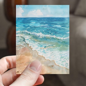 May include: A watercolor painting of a seascape with blue water, white foamy waves, and a sandy beach.