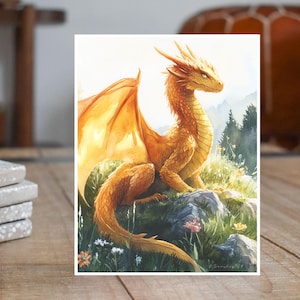 May include: A golden dragon with wings outstretched sits on a grassy hill. The dragon has a long, slender neck and a pointed snout. The background is a blurry landscape of mountains and trees.
