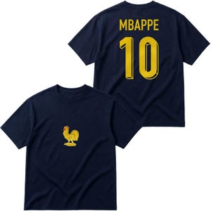 Pu&ograve; includere: Una t-shirt a maniche corte blu navy con una piccola grafica di un gallo dorato sul davanti. Il retro della maglietta mostra il nome MBAPPE in caratteri gialli sopra il grande numero 10 giallo, entrambi in un carattere tipografico grassetto.