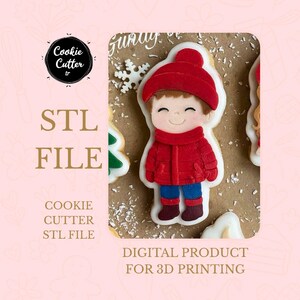 Può includere: Un design di taglia biscotti con un ragazzo sorridente con cappotto, cappello e sciarpa rossi. L'immagine include il testo "STL FILE" e "DIGITAL PRODUCT FOR 3D PRINTING". Il design è per un taglia biscotti.