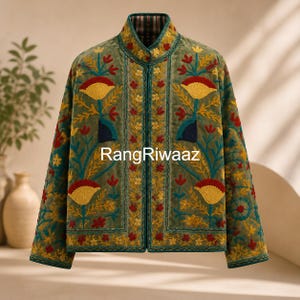 Puede incluir: Una chaqueta de color verde oliva de manga larga con cuello mao y un intrincado bordado floral en tonos amarillo, rojo y azul oscuro. El frente muestra el texto RangRiwaaz, con un patrón de borde vertical que enmarca la abertura central.