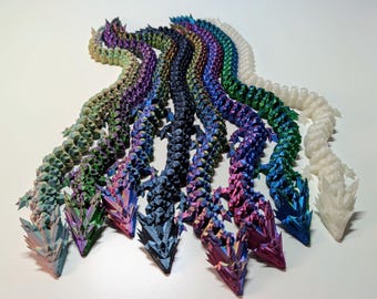 May include: A set of eight iridescent dragon figurines, each with a different color, arranged in a row. The dragons are made of a textured material and have a scaly appearance.