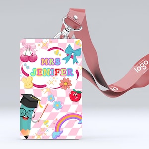 Könnte beinhalten: Ein personalisiertes Lehrer-ID-Abzeichen mit einem rosa-weiß karierten Hintergrund. Das Abzeichen zeigt den Namen "Mrs. Jenifer" in bunten Buchstaben sowie Cartoon-Illustrationen eines Bleistifts, Apfels, Regenbogens und anderer niedlicher Grafiken. Ein rosa Schlüsselband ist befestigt.