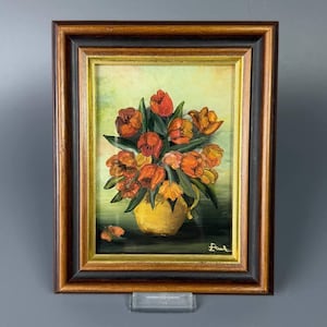 Può includere: Un dipinto a olio in una cornice di legno scuro con bordo dorato che raffigura un bouquet di tulipani arancioni e rossi in un vaso giallo su uno sfondo verde chiaro. La firma dell'artista "Etuk" è visibile nell'angolo in basso a destra.