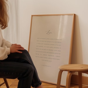 May include: A framed print with a beige background and black text. The text reads "Love is patient, love is kind. It does not envy, it does not boast, it is not proud. It does not dishonour others, it is not self-seeking, it is not easily angered, it keeps no record of wrongs. Love does not delight in evil but rejoices with the truth. It always protects, always trusts, always hopes, always perseveres, love never fails. 1 Corinthians 13."