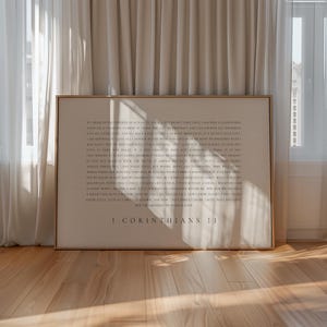 Peut inclure: Impression encadrée avec le texte de 1 Corinthiens 13. Le texte est de couleur marron clair sur un fond crème. Le cadre est de couleur marron chaud. L'impression est posée sur un sol en bois.