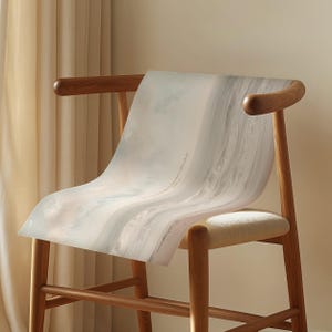 May include: A wooden chair with a light-colored woven seat and curved back. A large, light-colored print with a cloudy, abstract design is draped over the chair. The print has text that reads "If you walk through the fire, I will be with you."