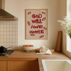 Puede incluir: Una impresión enmarcada con el texto "God Will Always Provide" en letras rojas. La impresión está rodeada de un marco de madera y tiene un fondo blanco. La impresión está colgada en una pared de una cocina.