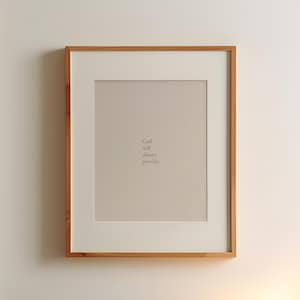 May include: A framed print with a light brown wooden frame. The print has a beige background with the text "God will always provide." printed in a light brown color.