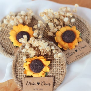 May include: Three burlap circles with sunflowers and dried flowers, each with a brown paper tag that reads "Elvin &hearts; Onur 18.09.2020".