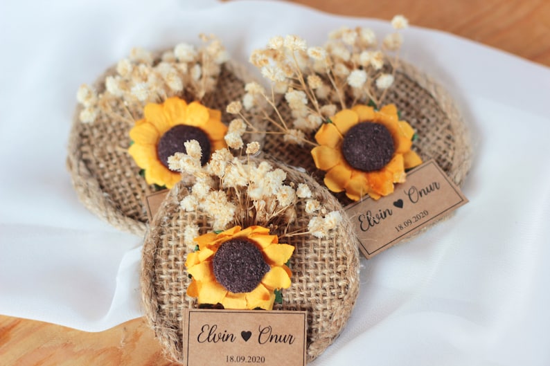 May include: Three burlap circles with sunflowers and dried flowers, each with a brown paper tag that reads "Elvin &hearts; Onur 18.09.2020".