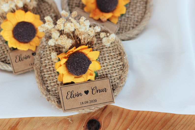 May include: Two burlap and brown paper favor tags with a sunflower and dried flowers. The tags are decorated with the text "Elwin &hearts; Onur 18.09.2020".