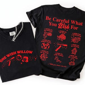 May include: Two black t-shirts with red graphics and text. One shirt says "One Wish Willow" and the other says "Be Careful What You Wish For" with various wish illustrations. A silver chain necklace is on the first shirt.