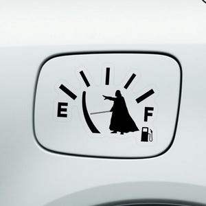 May include: Black and white vinyl decal featuring a fuel gauge design with a character silhouette pointing towards the empty mark. The decal is water-proof and designed for a car's fuel door.
