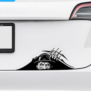 May include: A black vinyl decal applied to the white trunk of a vehicle. The graphic features a stylized illustration of a character wearing a fedora hat with a clawed hand emerging from behind, accompanied by a blue and white WATER PROOF label.
