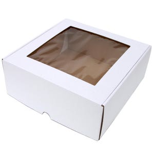 May include: A white cardboard bakery box with a clear window on the top. The box is square and has a simple, clean design. The window allows a view of the contents inside. The box is likely used for packaging cakes, pastries, or other baked goods.