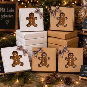 May include: Gingerbread cookies in decorative boxes. The boxes are white and brown, with a window cut-out in the shape of a gingerbread man. Each box is tied with a brown and white checkered bow. The image has a festive holiday theme.