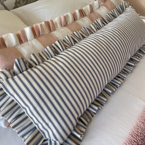 Navy and pink striped lumbar cushions sitting on a bed with white sheets and a pink bedspread