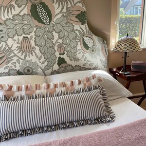 Navy and pink striped lumbar cushions sitting on a bed with a large floral headboard