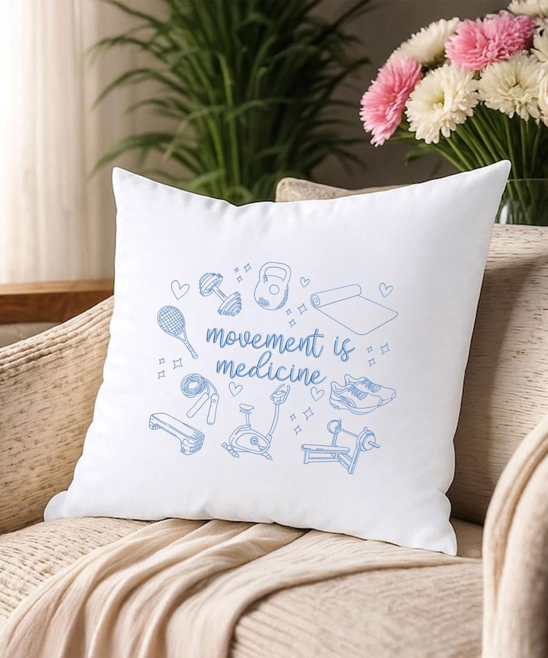 May include: White square pillow with a blue illustration of fitness equipment and the phrase "movement is medicine." The design includes dumbbells, a kettlebell, a yoga mat, a tennis racket, a jump rope, a bench, an exercise bike, and sneakers.