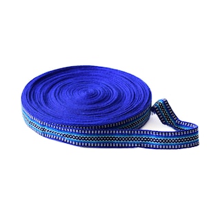 Puede incluir: Un rollo de cinta azul y blanca a rayas con un patrón tejido. La cinta está enrollada y lista para ser utilizada para manualidades o decoración.