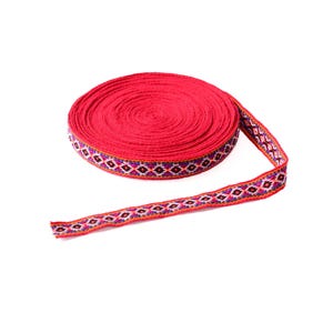 May include: A roll of red ribbon with a geometric pattern in shades of purple, orange, and white.
