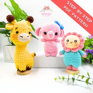 Puede incluir: Patrón de crochet PDF para tres juguetes amigurumi: una jirafa amarilla, un elefante rosa y una flor azul con una cara amarilla. El patrón se llama "Patrón PDF paso a paso".