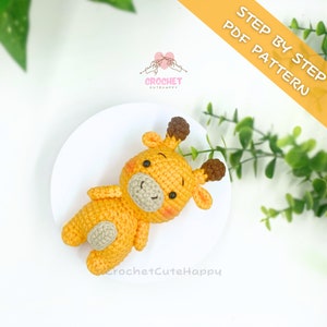 Könnte beinhalten: Ein gehäkeltes Giraffen-Amigurumi-Spielzeug mit braunen Ohren und einer hellbraunen Nase. Die Giraffe liegt auf einer weißen Oberfläche. Der Text "STEP BY STEP PDF PATTERN" ist in der oberen rechten Ecke des Bildes sichtbar.