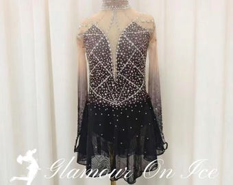 May include: Figure skating costume with a black and ombre design. The dress features a high neck, long sleeves, and is embellished with rhinestones. The skirt has a layered, ruffled hem. The text "Glamour On Ice" and "Figure Skating Costume by Chloe" are visible.