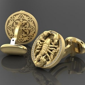 May include: A pair of gold cufflinks. One cufflink features a detailed, intricate design. The other cufflink features a scorpion with a diamond-encrusted border.