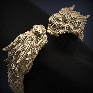 May include: A gold-toned bracelet with two dragon heads on either end. The bracelet is made of metal and has a detailed design.