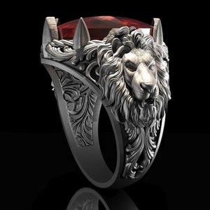 May include: A silver ring with a detailed lion head design and a red gemstone. The ring has intricate floral patterns and a textured finish.