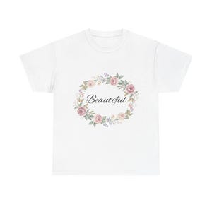 Könnte beinhalten: Weißes T-Shirt mit einem floralen Kranzdesign mit rosa Rosen und grünen Blättern. Das Wort "Beautiful" ist in Kursivschrift innerhalb des Kranzes geschrieben. Ein lässiges T-Shirt für den Alltag.