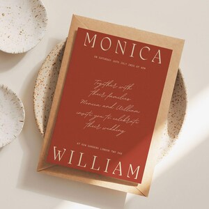 May include: A red wedding invitation with white text. The invitation reads "Monica and William together with their families invite you to celebrate their wedding at New Garden, London, TW1 2AA."