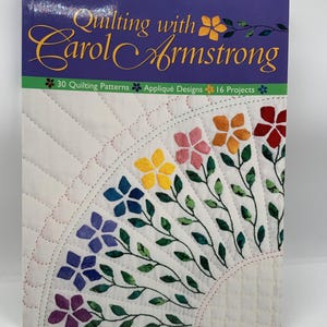 May include: A softcover book titled Quilting with Carol Armstrong, featuring 30 Quilting Patterns, Appliqué Designs, and 16 Projects. The cover displays a white quilted fabric background with a fan-shaped arrangement of colorful fabric flowers.