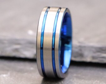 May include: A silver ring with two blue stripes around the band.