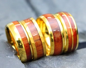 May include: Four gold rings with a wood inlay. The rings are stacked on top of each other. The wood inlay is a reddish-brown color.