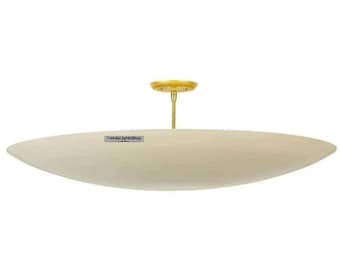 May include: A large, off-white, oval-shaped ceiling light fixture with a brass finish. The light fixture is suspended from the ceiling by a single, thin, brass rod.