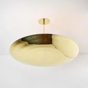 May include: A gold-toned, round, saucer-shaped pendant light fixture with a small, round, gold-toned canopy.