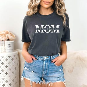 May include: A dark gray t-shirt with the word "MOM" printed in white with hearts and names "Sarah, Michael, David,  Caroline" underneath.