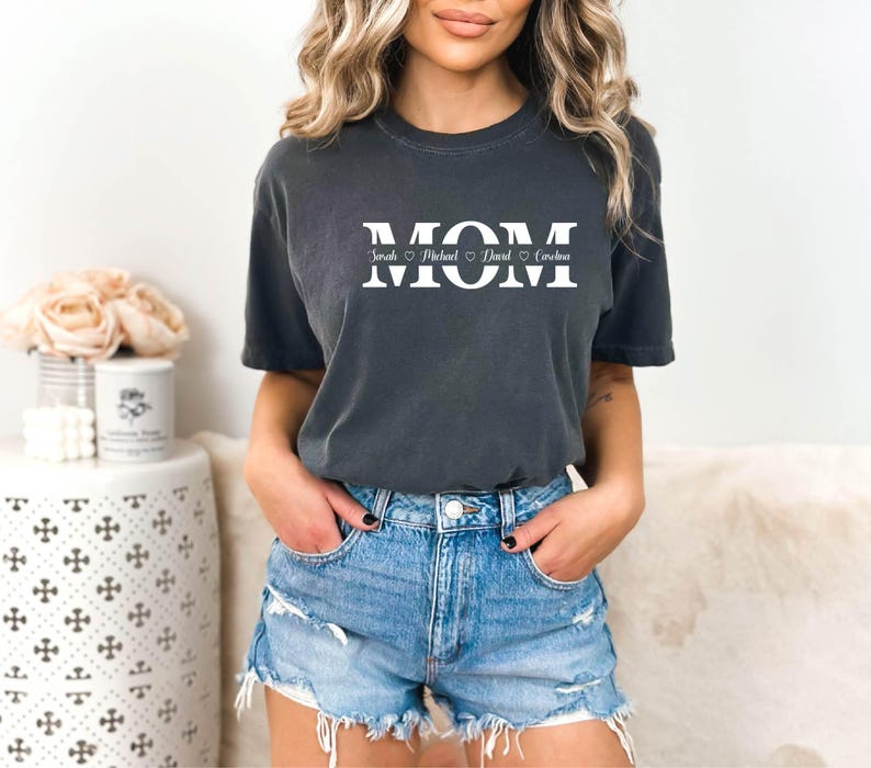 May include: A dark gray t-shirt with the word "MOM" printed in white with hearts and names "Sarah, Michael, David,  Caroline" underneath.