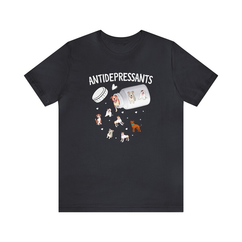 May include: Black t-shirt with the word "ANTIDEPRESSANTS" above an illustration of a pill bottle spilling out cartoon dogs. The dogs are various breeds and colors, with hearts scattered around them.